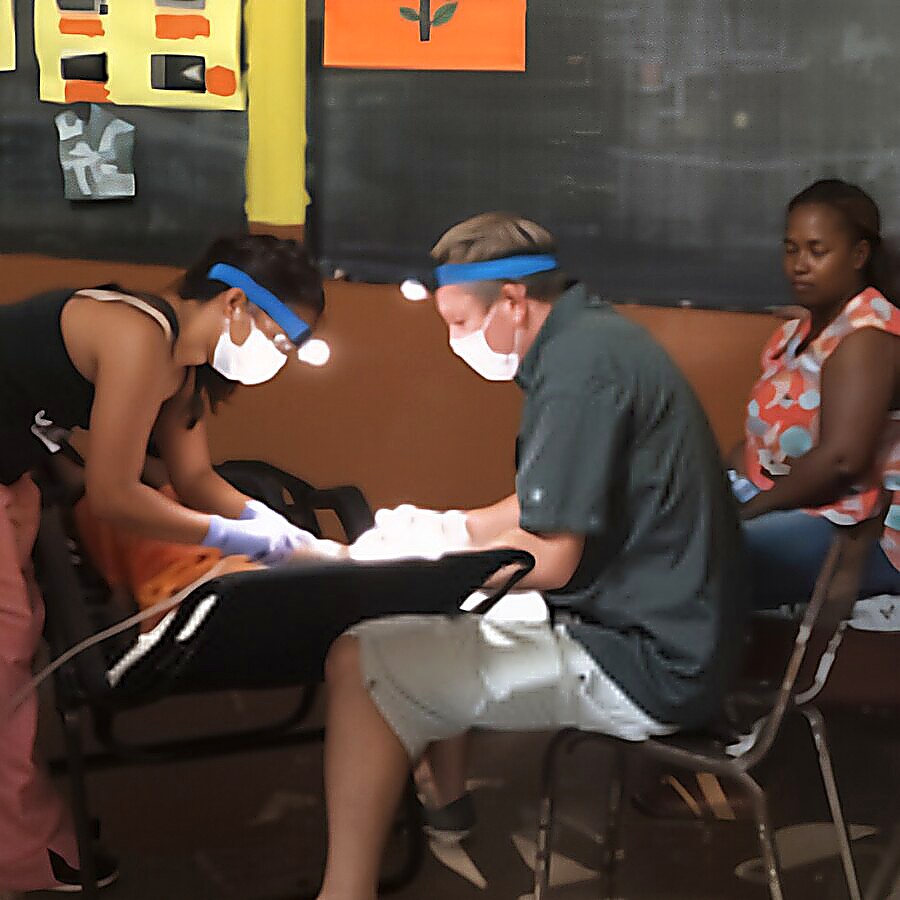 Dr. Will and a volunteer treating a patient in the classroom clinic