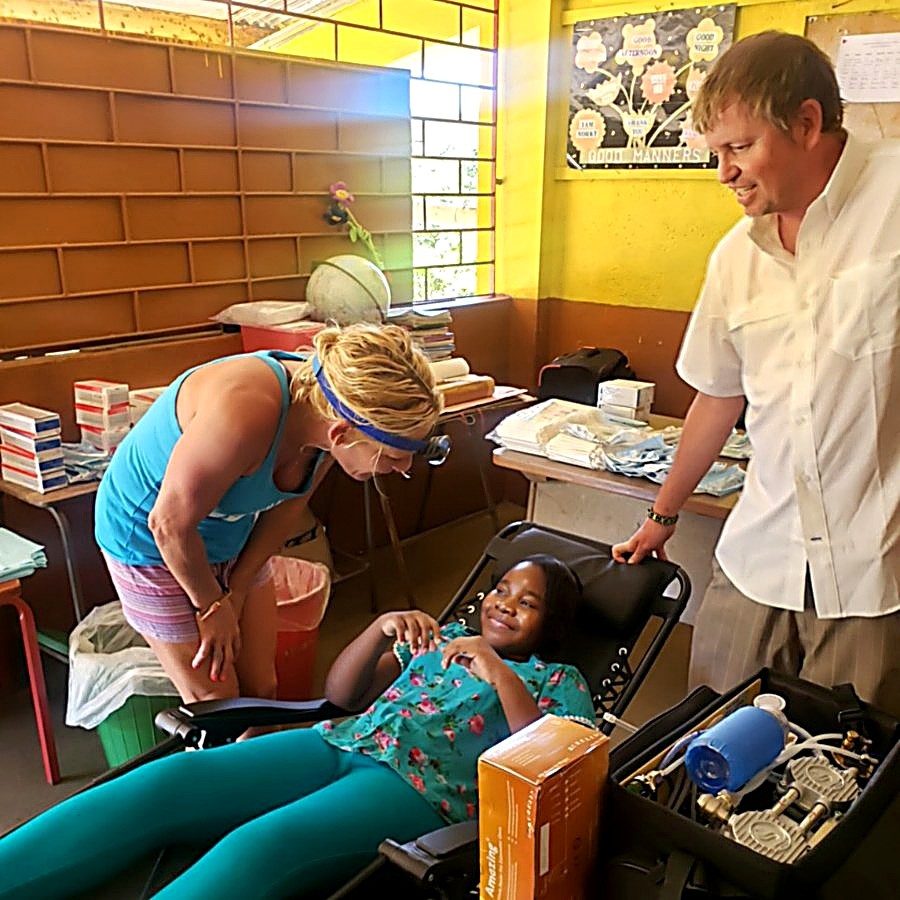 A young patient smiling in the treatment chair as a volunteer prepares
